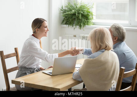 Smiling lawyer or financial advisor handshaking senior couple at Stock Photo