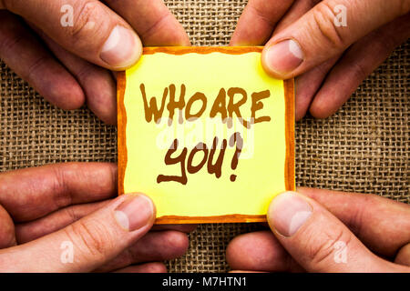 Conceptual hand writing showing Who Are You Question. Business photo showcasing Personality Identity Profile, About Me Or You  written on Sticky Note Paper Holding Hand with Finger. Stock Photo