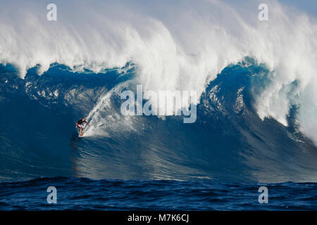 A tow-in surfer drops down the face of Hawaii's big surf at Peahi (Jaws) off Maui. Stock Photo