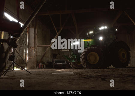 Old barn with a modern green tractor inside Stock Photo