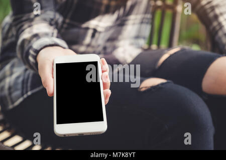 Mockup image of a hand holding and giving white mobile phone with blank black desktop screen to someone in cafe Stock Photo