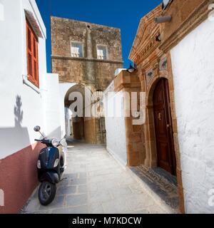 LINDOS, GREECE - MAY 06: Black retro Vespa scooter parked in narrow street of medieval Old Town on May 06, 2016 in Lindos, Greece. Stock Photo