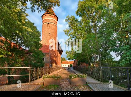 Bridge with love padlocks over Lyna river, Gothic castle of the Prince-Bishopric of Warmia in the background, Olsztyn, Poland Stock Photo