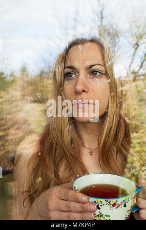 Portrait of depressed woman drinking glass of wine alone at home ...