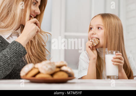 Photo of mother and daughter eating cookies and smile. Stock Photo