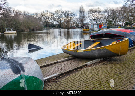 Winter at the boating lake in Finsbury Park, North London, UK, out of season with upturned boats, one sunken Stock Photo