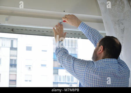 Man attaching elements with a screwdriver in order to install a blind Stock Photo