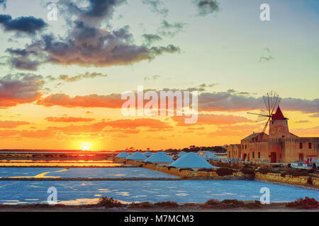 Sunset at Windmill in the salt evoporation pond in Marsala, Sicily island, Italy Stock Photo