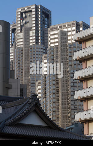 Tokyo Metropolitan Government Towers behind apartment buildings and a shrine roof in Shinjuku, Tokyo, Japan. T Stock Photo