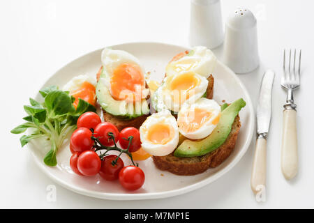 Egg and avocado toasts on white plate, closeup view. Concept of healthy breakfast, healthy lifestyle, dieting, fitness, weight loss, vegan, vegetarian Stock Photo