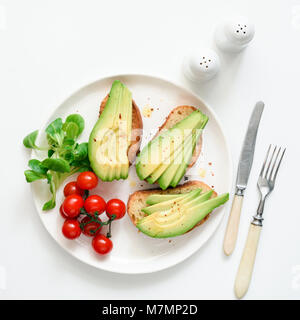 Avocado toasts, cherry tomatoes and salad on white plate, top view, square crop. Healthy lifestyle, vegen, vegetarian, dieting and weight loss concept Stock Photo