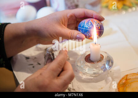 Removing wax from hand painted easter egg. Preparation for Easter holiday. Stock Photo