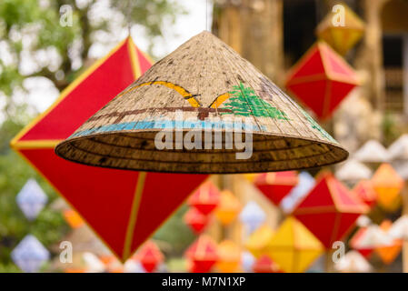 Paper lanterns to celebrate Chinese New Year hanging with a traditional bamboo conical hat in Hoàng thành (Imperial City) a walled citadel built in 1804 in Hue, Vietnam. Stock Photo