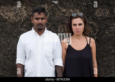 Emotional portrait of young just married couple. They stand near the wall and look on camera Stock Photo