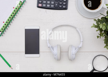 Office desk table layout with headphones and smartphone. Flat lay listening music composition on white wooden background Stock Photo