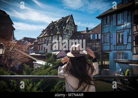 Young unrecognizable woman standing back on city promenade with beautiful view and inspired. Elegant female tourist explore old town in sunny day Stock Photo