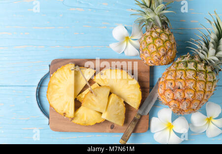 fresh sliced pineapple on wood block and blue wood background, summer fruits concept Stock Photo