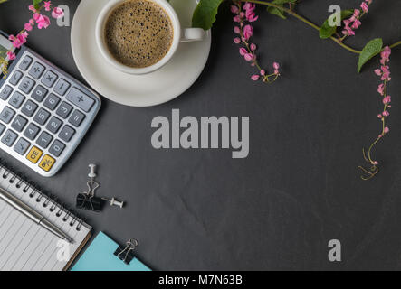 Office black stone desk table with calculator, black coffee and pen and pink flower creeper,  business background concept and copy space Stock Photo