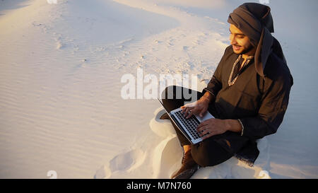 Successful Emirati businessman reads business plan and sits on w Stock Photo