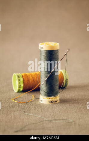 Two rolls of colorful threads with sewing needle Stock Photo