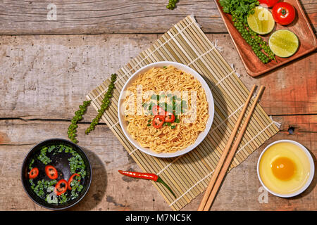 instant noodles in bowl with vegetable on wooden table. Stock Photo