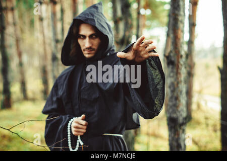 the black monk pointing his finger in the woods Stock Photo