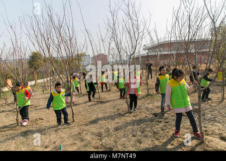 Rugao, Rugao, China. 11th Mar, 2018. Rugao, CHINA-11th March 2018: Children plant trees in Rugao, east China's Jiangsu Province, marking Tree Planting Day which falls on March 12th every year. March 12th is China's annually National Tree-planting Day. On this day, millions of Chinese, from all walks of life, will put their works at hands aside for a moment, take shovels and buckets as well as saplings, and trek out to green up their hometowns. First created by the US agriculturist Sterling Morton in 1872, Tree-planting Day was set in order to inspire people's passions for planting and protect Stock Photo