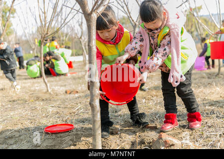 Rugao, Rugao, China. 11th Mar, 2018. Rugao, CHINA-11th March 2018: Children plant trees in Rugao, east China's Jiangsu Province, marking Tree Planting Day which falls on March 12th every year. March 12th is China's annually National Tree-planting Day. On this day, millions of Chinese, from all walks of life, will put their works at hands aside for a moment, take shovels and buckets as well as saplings, and trek out to green up their hometowns. First created by the US agriculturist Sterling Morton in 1872, Tree-planting Day was set in order to inspire people's passions for planting and protect Stock Photo