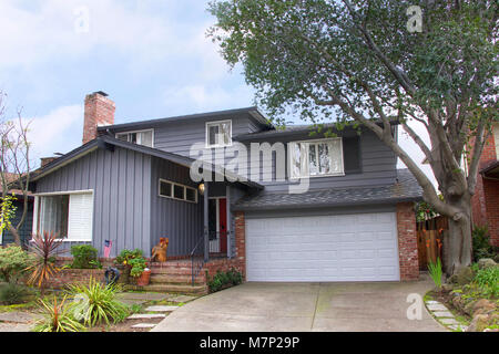 Two story ranch style house, gray wood siding with red brick work. Ranch style  is a domestic architectural style originating in the United States. Stock Photo