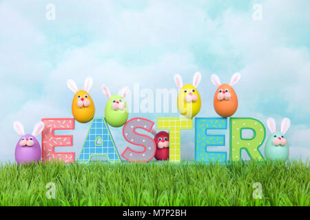 Colorful decorated Easter Eggs with bunny faces and ears sitting on and around decorative letter blocks spelling EASTER. Fun holiday concept. Stock Photo