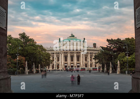 Long shot of Burgtheater in Vienna framed through the arch of Rathaus as the theatre lights come on Stock Photo