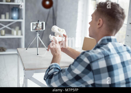 Professional blogger showing a dinosaur skull on cam Stock Photo