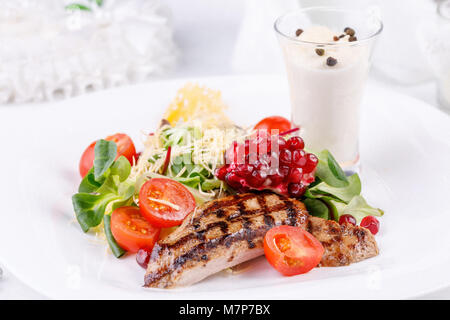Pork steak with pomegranate decorated with cherry tomatoes and micro-green. Close-up. Stock Photo