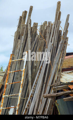 Old used and weathered planks of wood in a yard outdoors wirh a rusty ladder. Isolated. Stock Photo