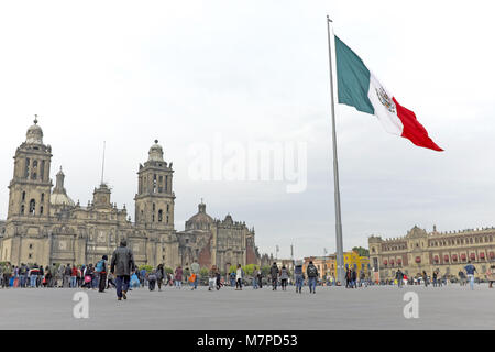 The national flag of Mexico waves above the Mexico City zocalo, the public square flanked by the National Palace and the Cathedral of Mexico City. Stock Photo