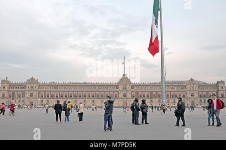 People wander around the Plaza de la Constitucion with the National Palace in the background of the main square in Mexico City, Mexico. Stock Photo