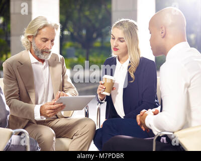multiethnic coporate people meeting discussing business using digital tablet in modern building. Stock Photo