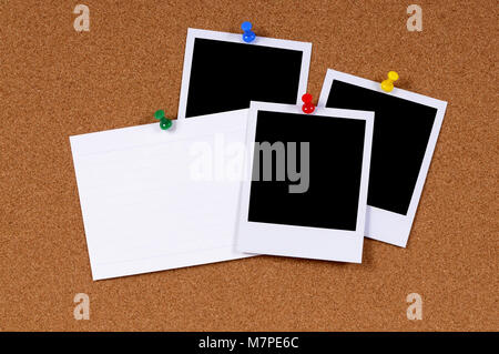 Blank polaroid style photo prints with office index card pinned to a cork bulletin board. Stock Photo