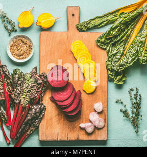 Colorful sliced beetroot on cutting board.  Red and yellow beetroot  with chard  leaves and ingredients on kitchen table background, top view. Vegan o Stock Photo