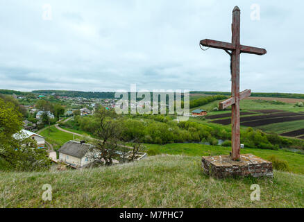Wooden christianity religious cross near Rukomysh Cave temple and spring country fields and village, Buchach District, Ternopil Region, Ukraine. Stock Photo