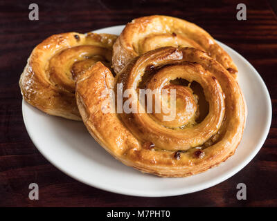 Close up of French raisin pastries on a white plate and wooden table Stock Photo