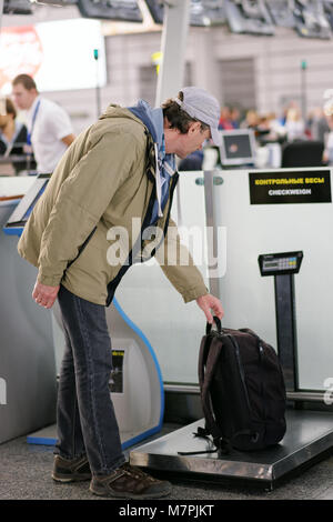 Passenger checking the weight of his luggage in the airport before the check-in Stock Photo
