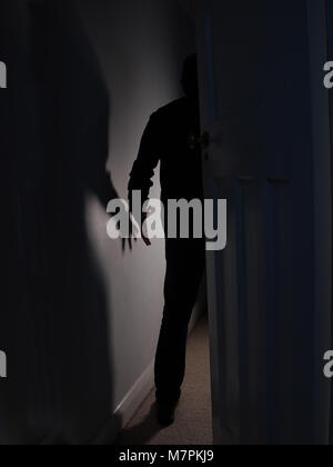 Shadow of a man holding arm out entering a dark room Stock Photo