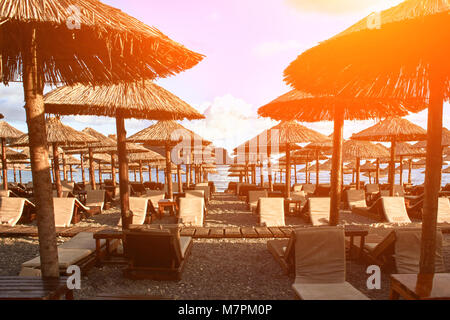 Sun loungers and umbrellas are on the beach in Budva, Montenegro. Sun flare Stock Photo