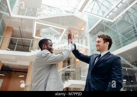 Celebrating success. Two young multiethnic businessmen giving each other high-five, celebrate great deal Stock Photo