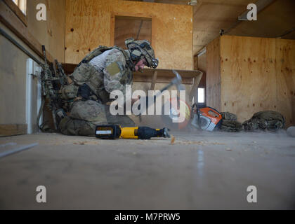 U.S. Air Force Senior Airman Joseph Brady, 83rd Expeditionary Rescue Squadron pararescue team member, hammers boards on a building’s floor during a mission rehearsal at Bagram Airfield, Afghanistan Aug. 26, 2014.  During the rehearsal, the pararescuemen breached and cleared a building to rescue a simulated casualty. Brady is deployed from Davis-Monthan Air Force Base, Ariz. and a native of Phoenix, Ariz.  (U.S. Air Force photo by Staff Sgt. Evelyn Chavez) 455th Air Expeditionary Wing Bagram Airfield, Afghanistan Stock Photo