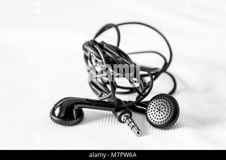 Black headphones tangled isolated on white background Stock Photo