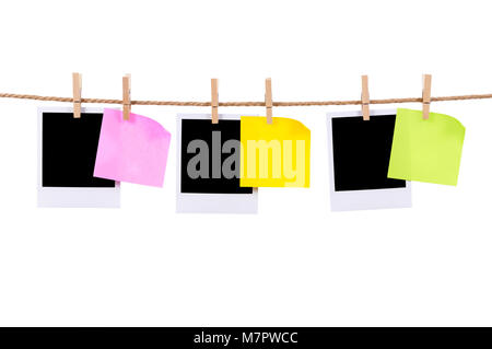 Blank instant camera photo prints and office sticky notes hanging on a rope or string isolated against a white background.  Space for copy. Stock Photo