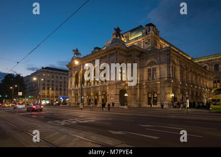 Wide shot of traffic passing in front of the Vienna Opera House on Opernring. Taken early evening in September as the city lights are coming on Stock Photo