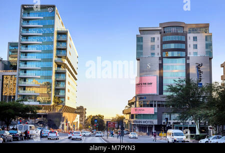 Johannesburg, South Africa - March 8, 2018: Modern glass fronted buildings with cars in the foreground. Stock Photo